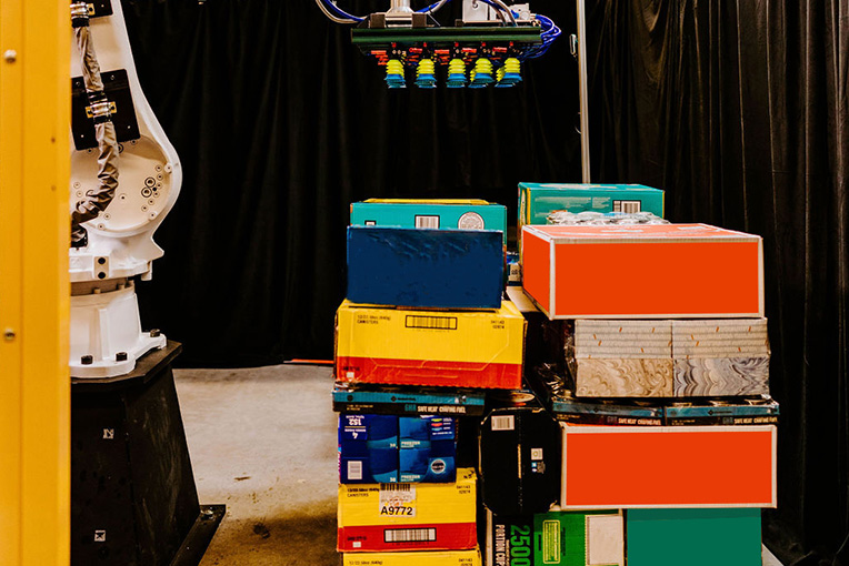 A photo of a robotic arm next to a mixed pallet